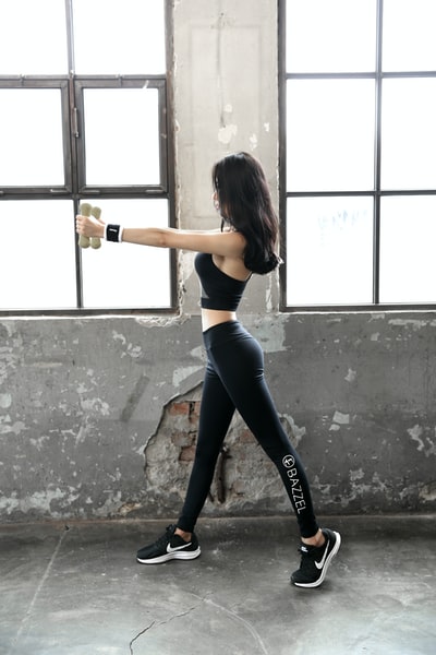 Dressed in a black sports bra and black tights with a bottle of woman
